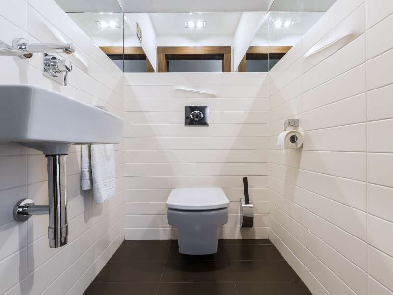 Modernes Badezimmer mit neuen Armaturen, Toilette und vollständig gefliesten Wänden und Boden.