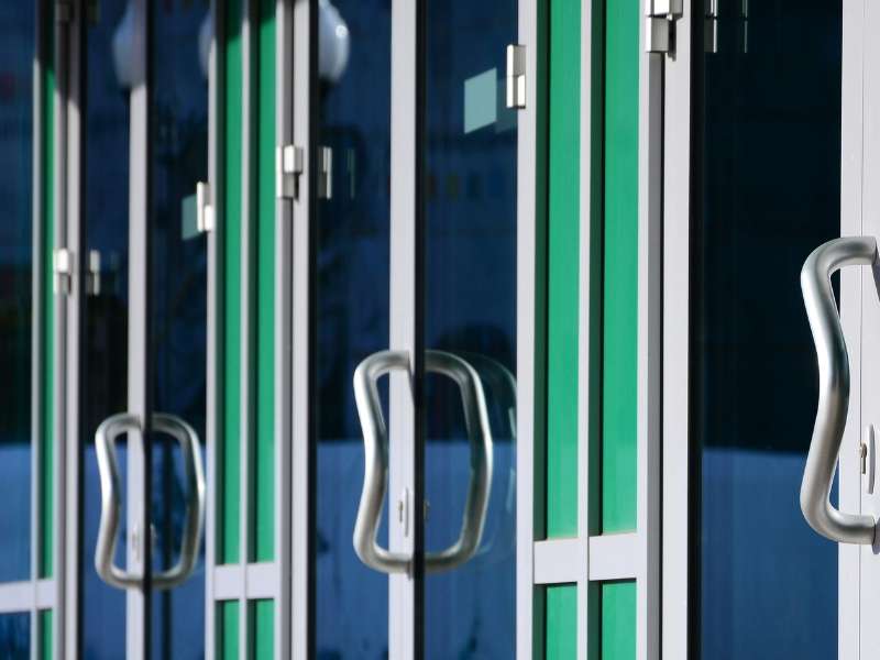Mehrere nebeneinanderliegende Türen in einem öffentlichen Gebäude, typisch für Schulen oder Universitäten.