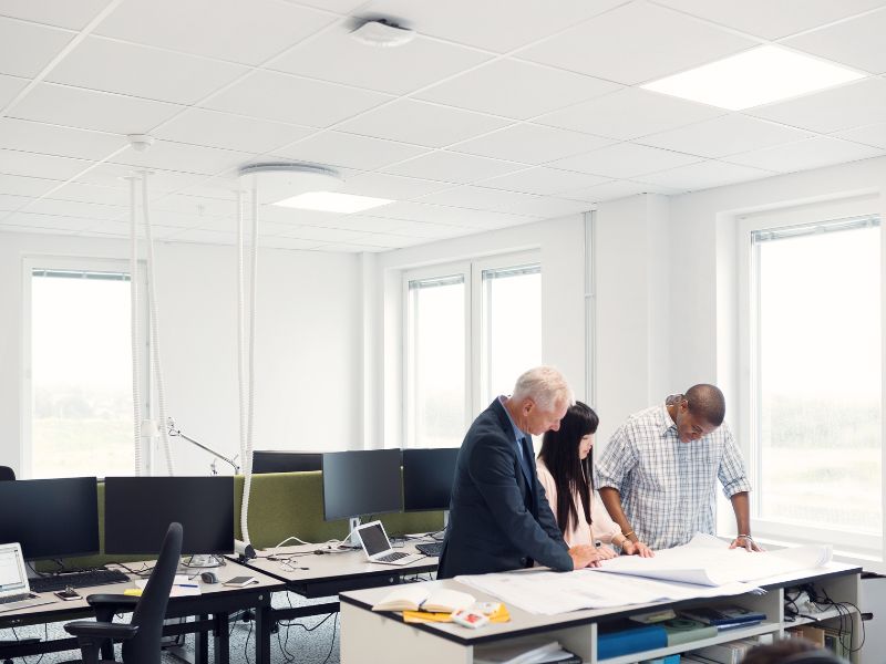 Drei Personen stehen in einem modernen Büro mit neu errichteten Trennwänden.
